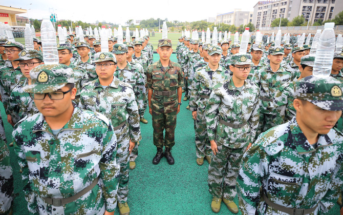 9月2日，在湖南省衡阳市南华大学雨母校区，李俊（中）头顶水瓶与同学们一道站军姿