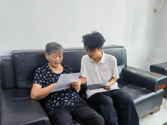 图为实践团成员为社区老人细致解读资助政策