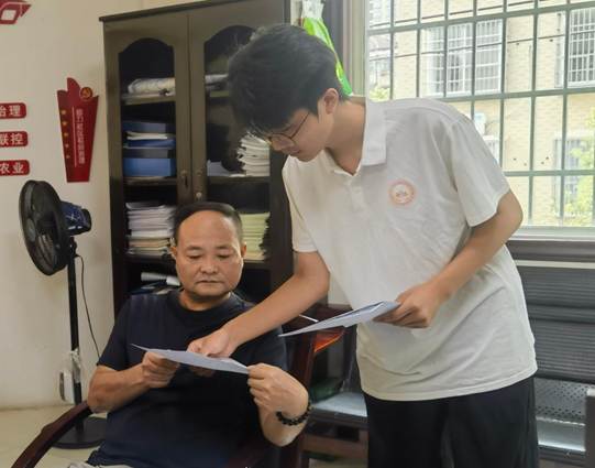 图为实践团成员向新和社区工作人员发放资助政策宣传手册并讲解相关政策